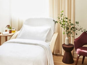 Flagship sollis location patient care bed with side tables and chair next to it
